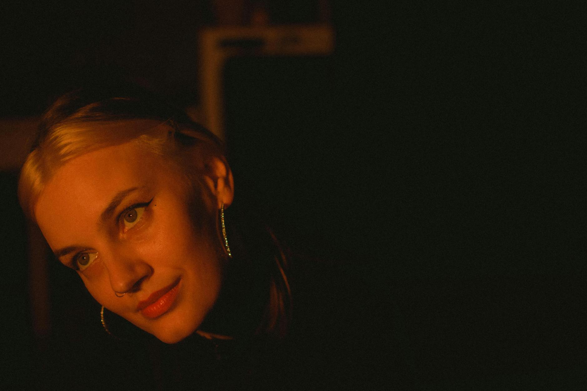 Moody warm-toned portrait of a young woman with blonde highlights, shot at night.
