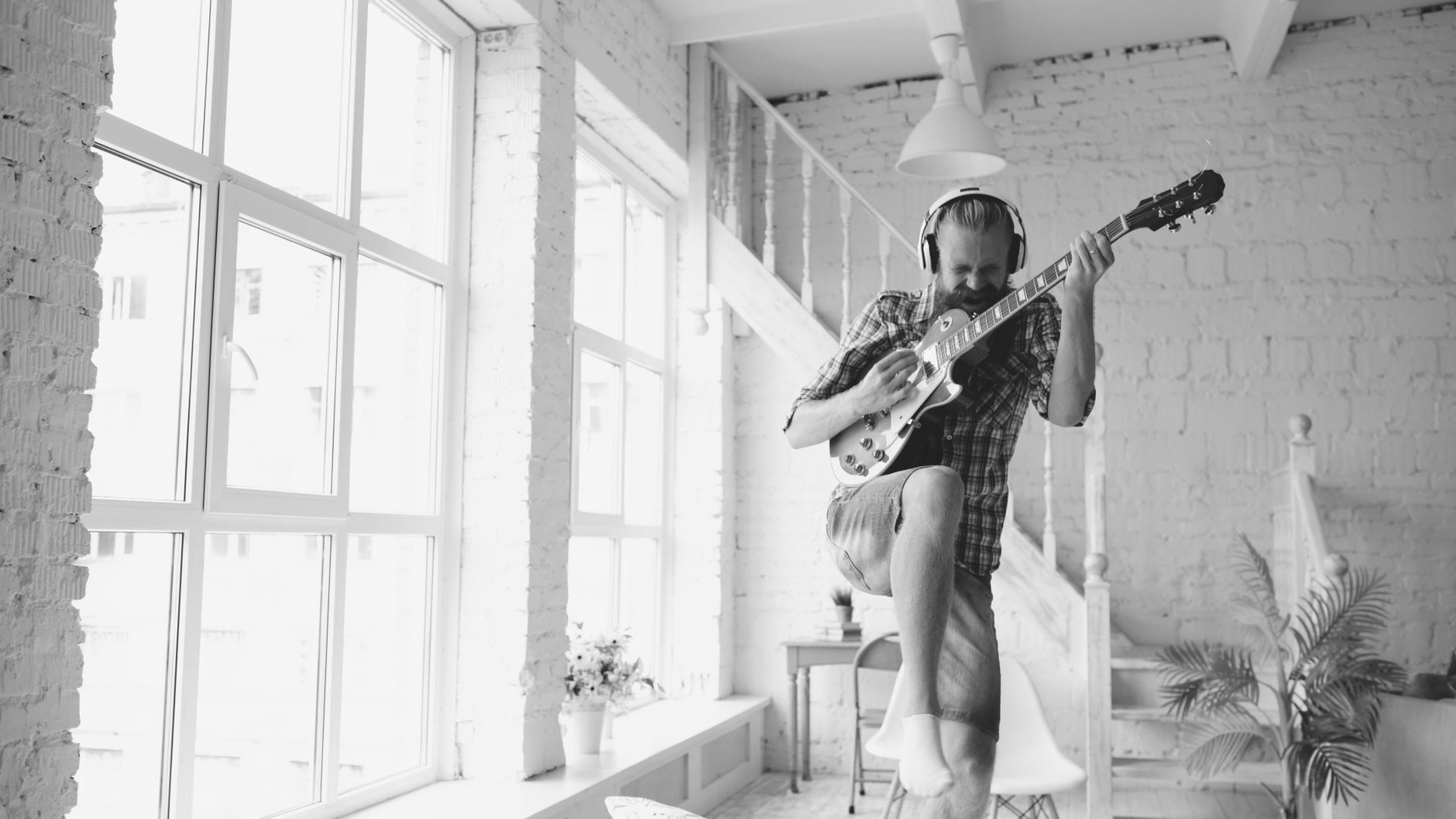 Man passionately playing electric guitar indoors, adding a lively vibe.