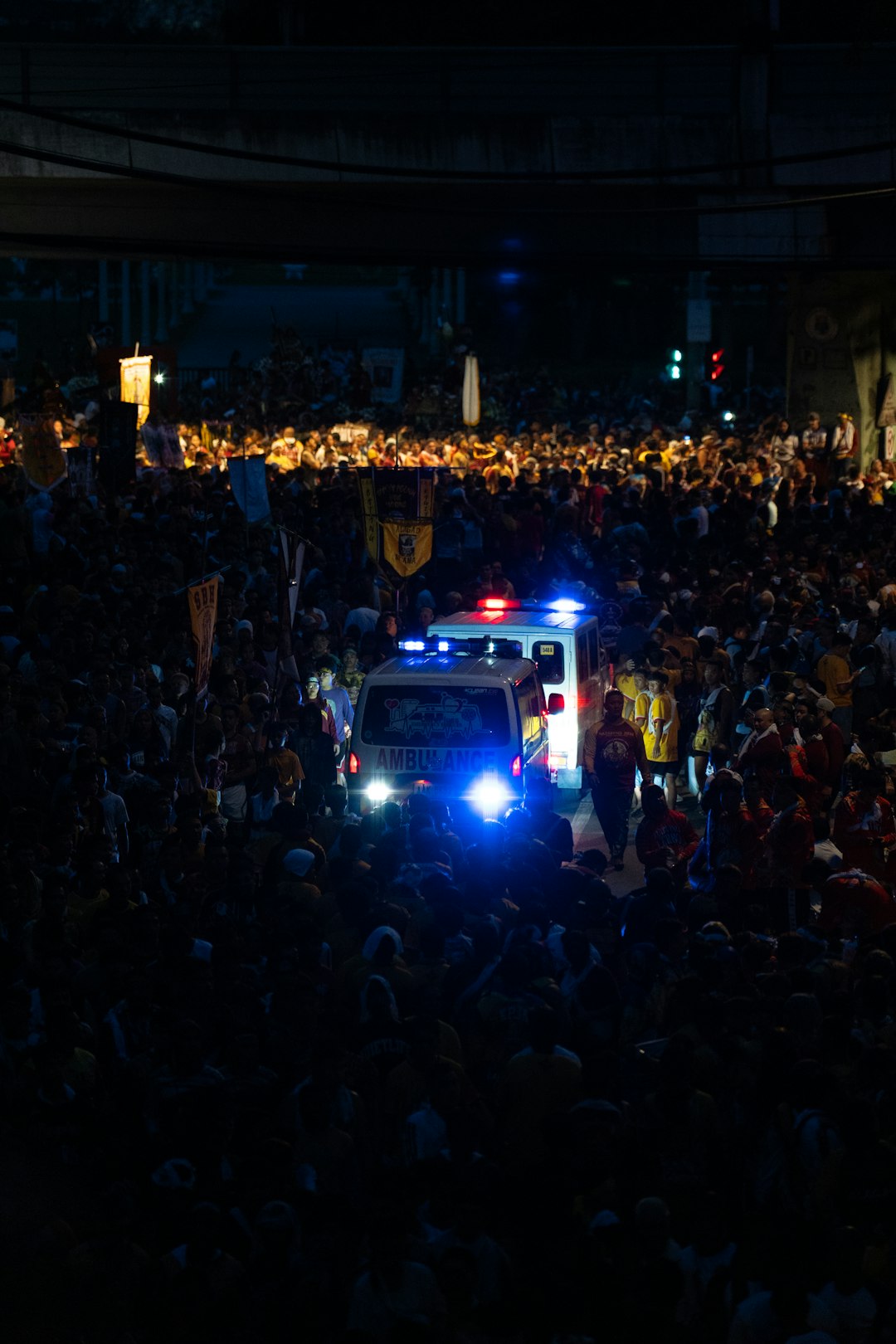 Ambulance with flashing lights in a crowded street at night.